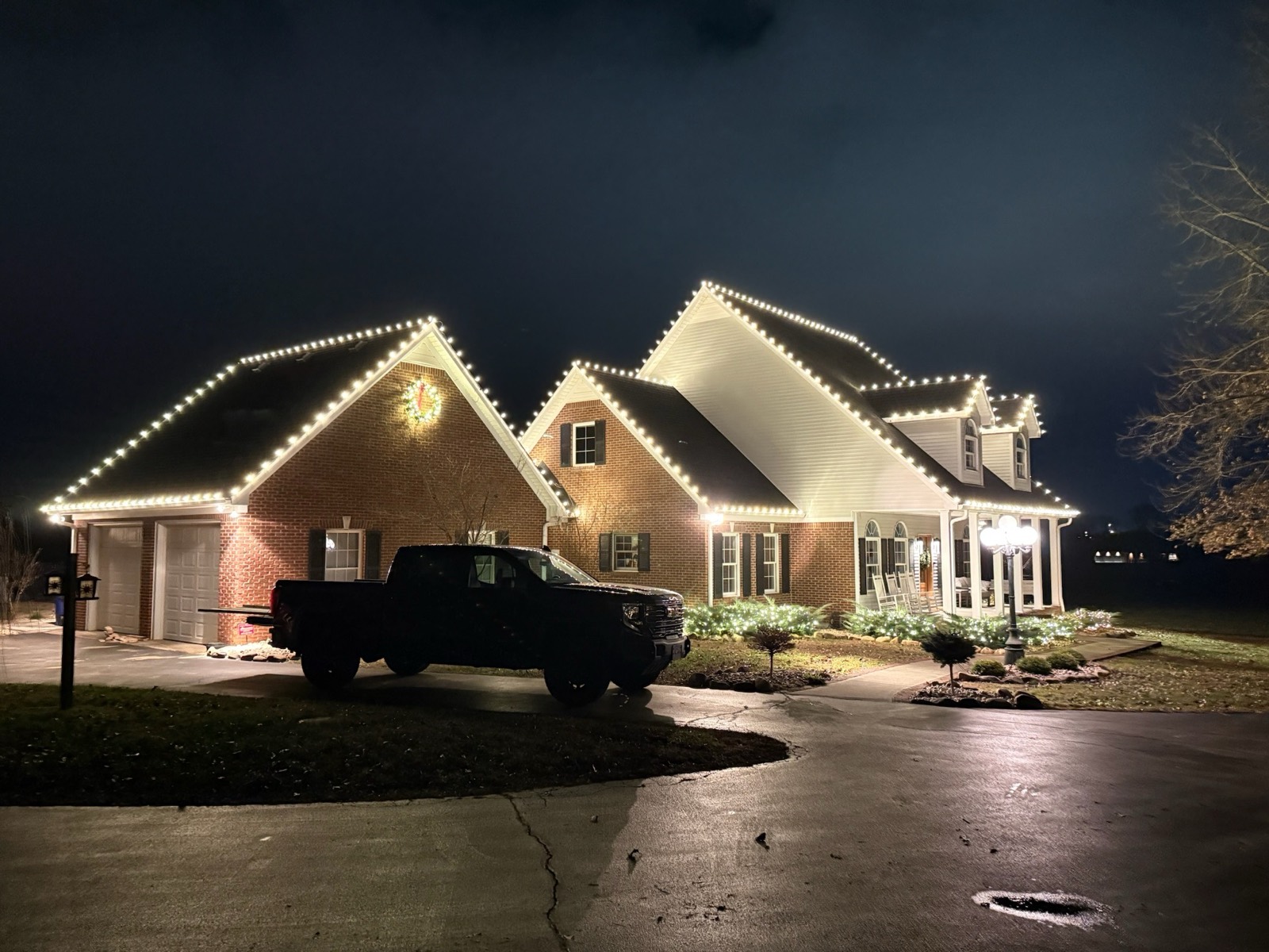 Triple gable brick home traced in warm white C9 holiday lighting, Bowling Green KY